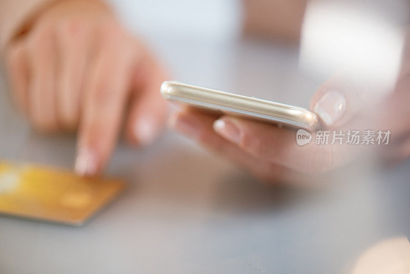 女性使用智能手机和信用卡的手的特写