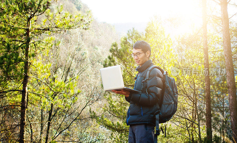 徒步旅行者在森林中使用笔记本电脑