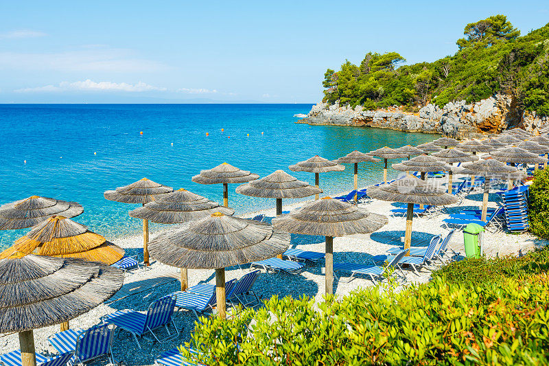 斯科佩洛斯岛私人海滩上的躺椅和雨伞