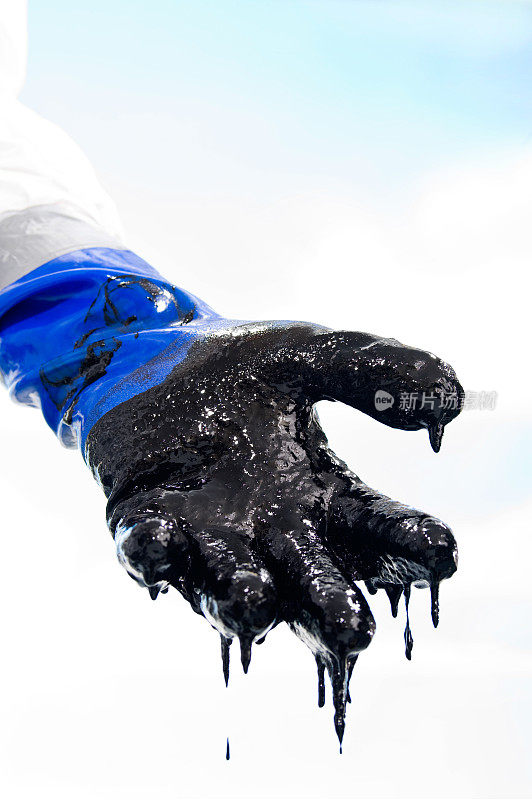 在清理油污时，戴着手套的手沾满油污
