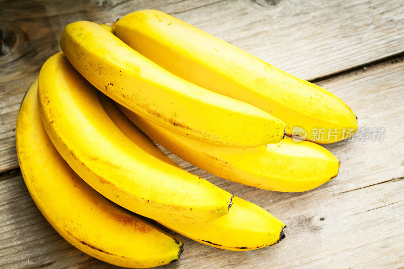 木头表面上挂着一串熟透的鲜黄色香蕉