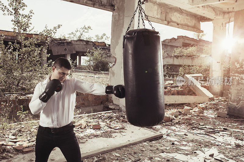 商人打拳击袋，在废墟中锻炼。
