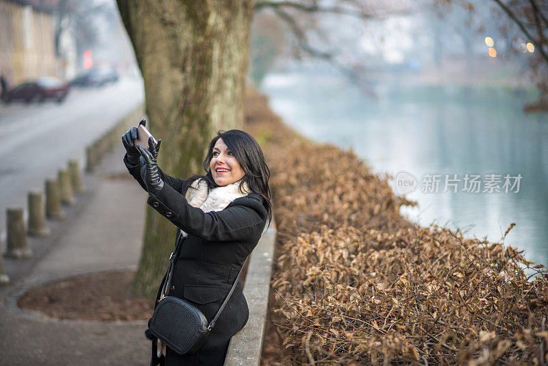 微笑的女人在河边自拍