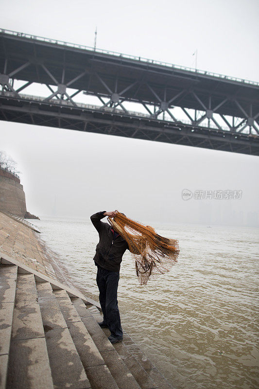 渔夫在长江上撒网，后面是桥