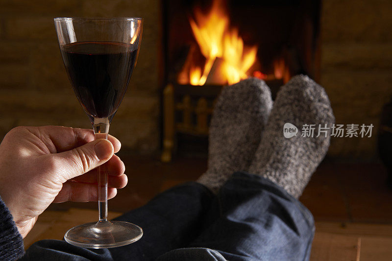 拿着一杯红酒在火边放松的男人