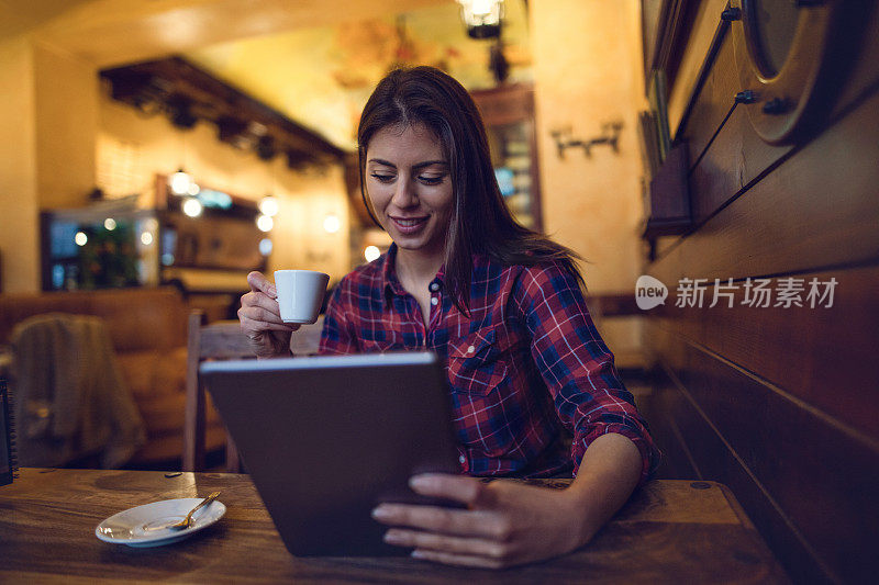 快乐的女人一边喝咖啡一边用触控板。