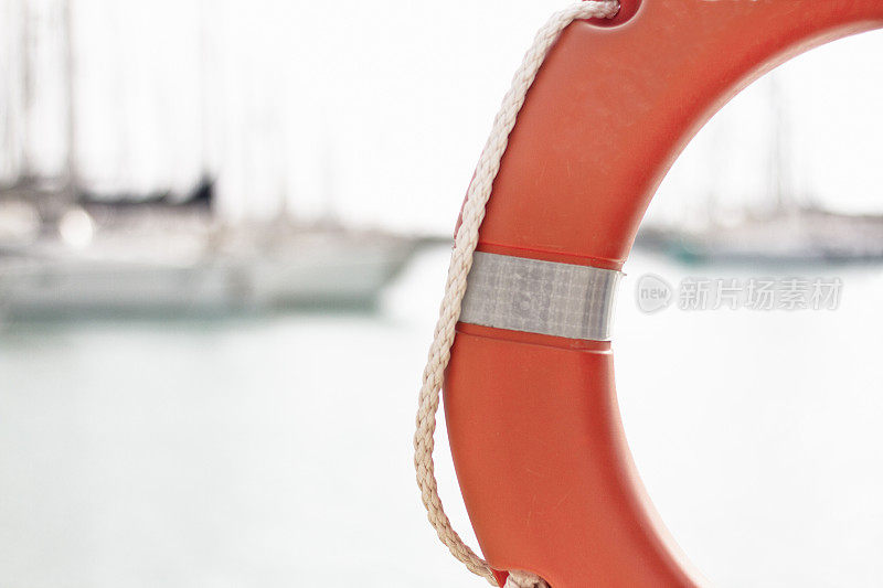 橙生活Preserver-Ring;模糊背景中的大海和帆船
