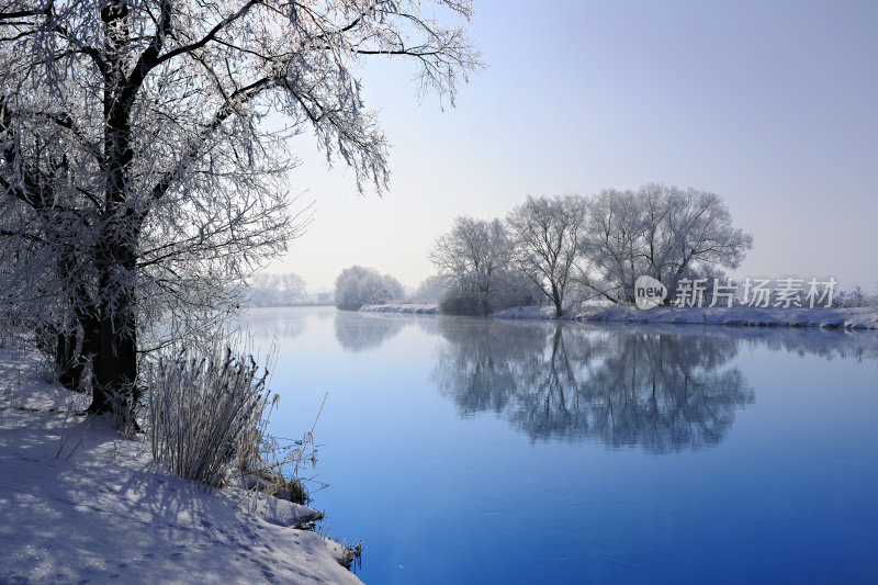 冰冻的冬季景观与树木倒映在河里