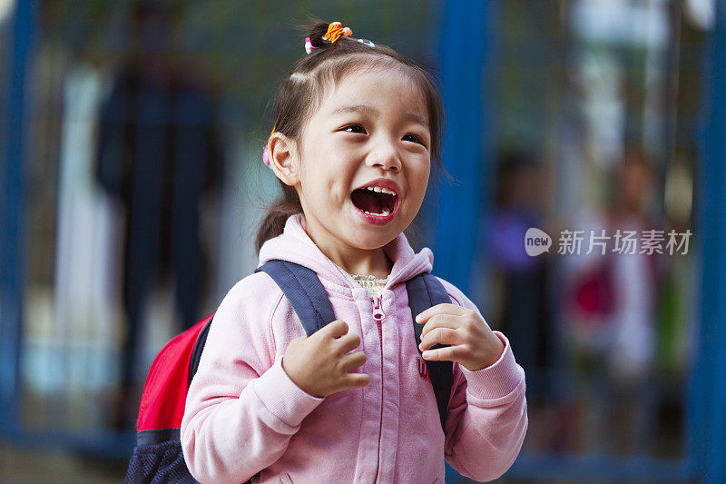 快乐的小女孩拿着书包在学校