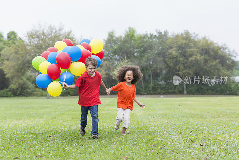 孩子们在公园里拿着一堆气球奔跑