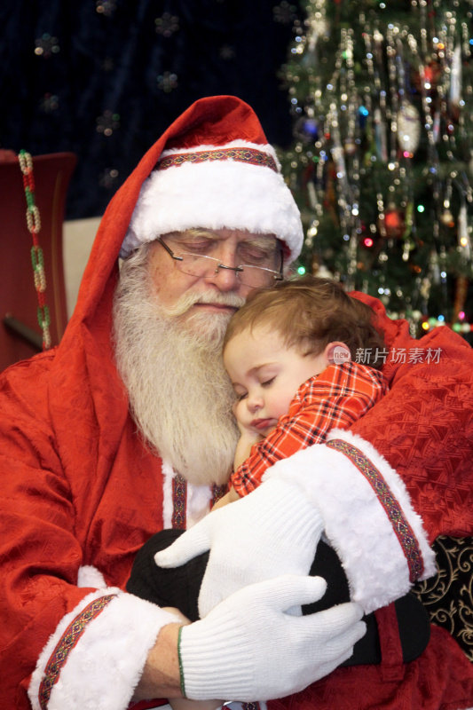 圣诞老人在休息，孩子在他的腿上打盹