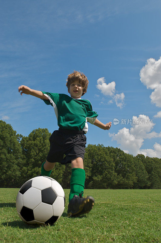 穿着绿色衣服的男孩正在踢足球