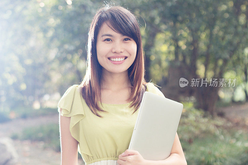 亚洲女学生在校园里用笔记本电脑的肖像