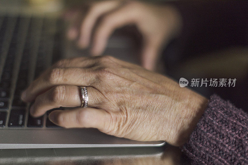 一个面目全非的59岁女人的手，当时她正在咖啡馆里用笔记本电脑工作。