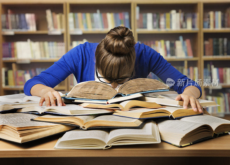 学习的学生睡在书上，疲惫的女孩看书，图书馆