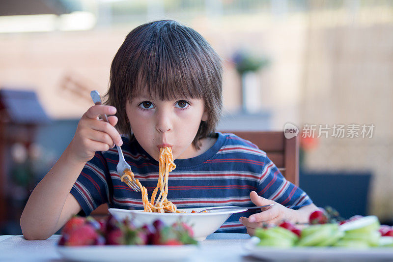 可爱的孩子，学前班的小男孩，午餐在户外吃意大利面