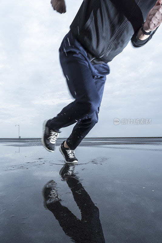 照片中的男运动员跑过水坑对着多云的天空