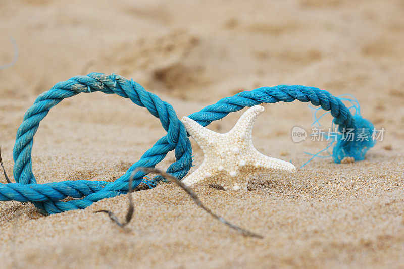 在海边的沙滩上，一条蓝色的编织绳和一只海星