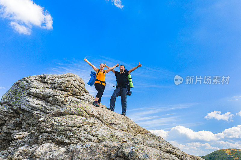 一对夫妇在一块石头上举起手来。