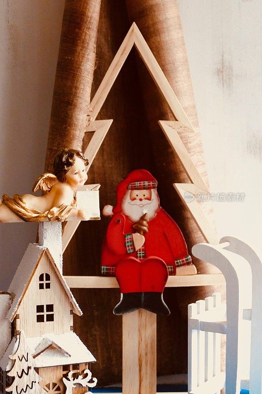 圣诞老人坐在一棵木制的抽象圣诞树下，天使在看书
