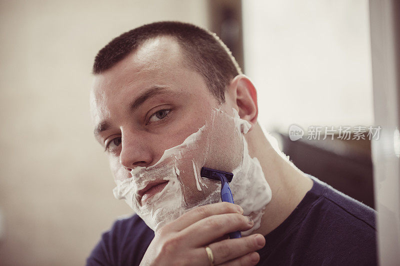 男人在浴室里用剃须刀刮胡子