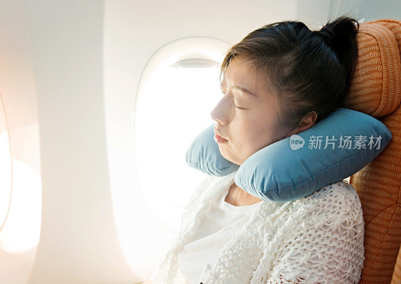年轻的亚洲女人在飞机上睡觉