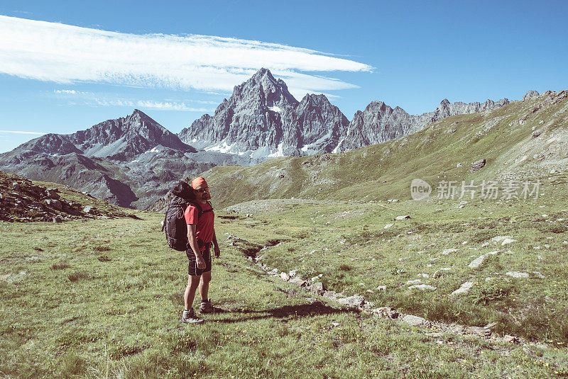 一个人在看壮丽的景色，在日落时，在阿尔卑斯山的山顶。后视图，色调和过滤图像，焦点在背景。