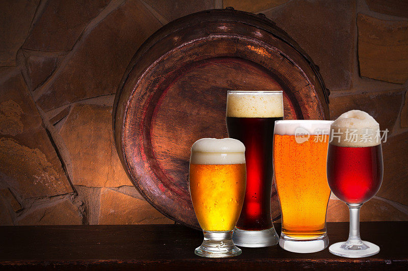 酒窖、酒吧、餐厅的各种啤酒。啤酒杯，旧啤酒桶和砖墙的背景。淡啤酒静物