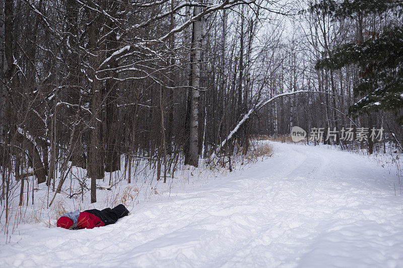 冬天，男孩脸朝下躺在林荫路上
