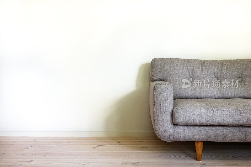 在简单的客厅内部，复古沙发靠在空的白色墙壁上