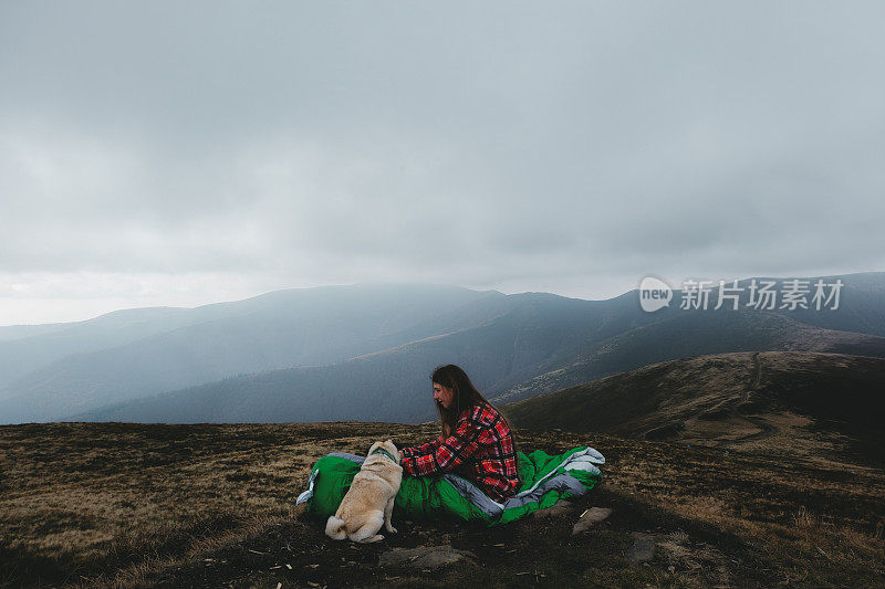 睡袋里的女人和狗在山中醒来