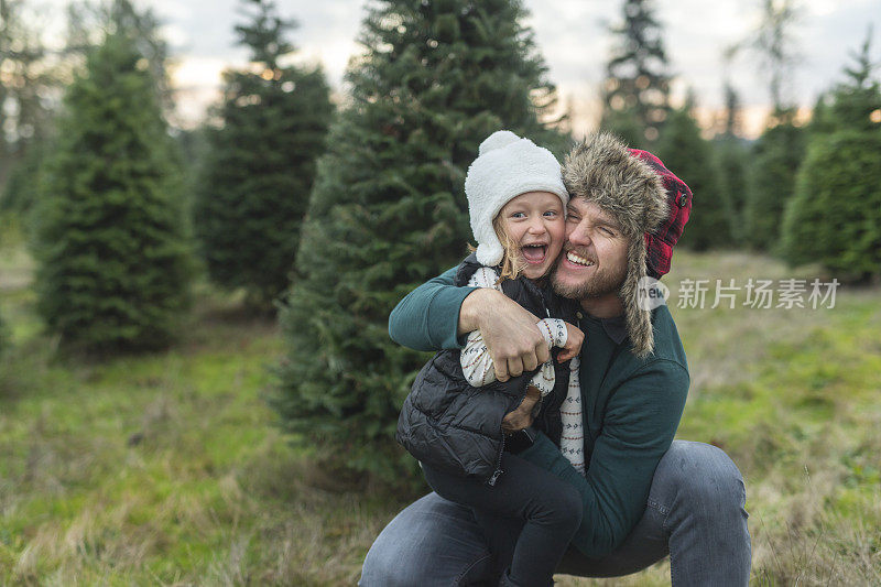 父亲在圣诞树农场拥抱他的女儿