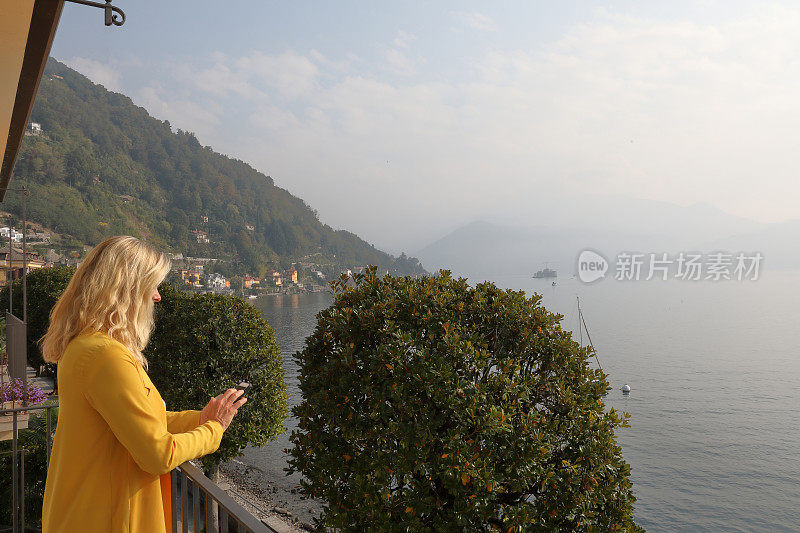 一个女人站在阳台上，眺望着湖面