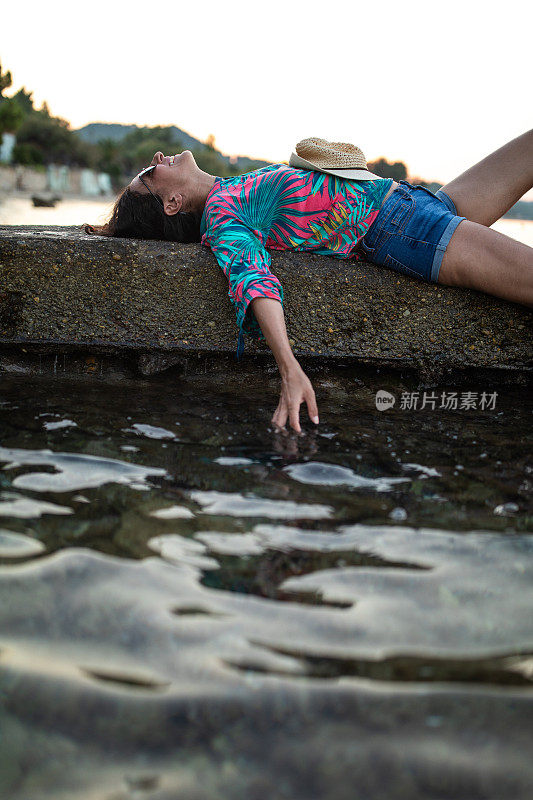 一个女人躺在海边的码头上