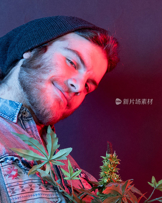年轻的瘾君子和大麻植物站在一起