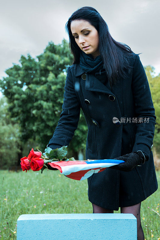 阵亡士兵的遗孀在墓地举着美国国旗