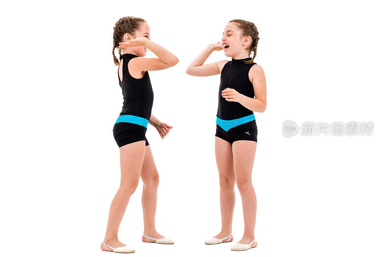 双胞胎女孩在白色背景下练习艺术体操。