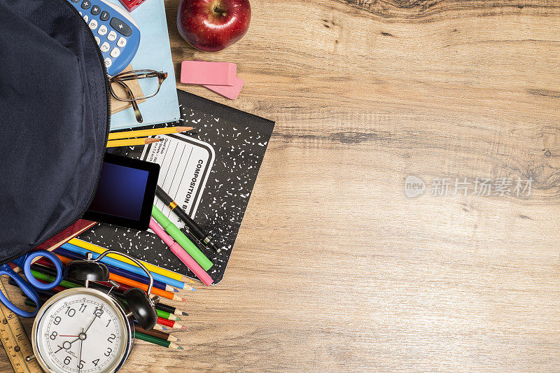 回到学习用品，背包放在木制的学生书桌上。