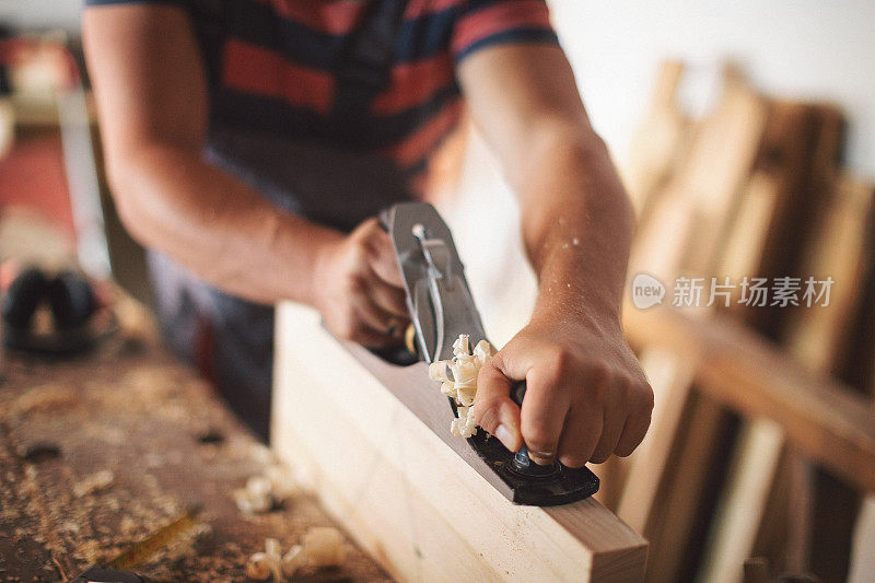 年轻的木匠正在打磨木桌