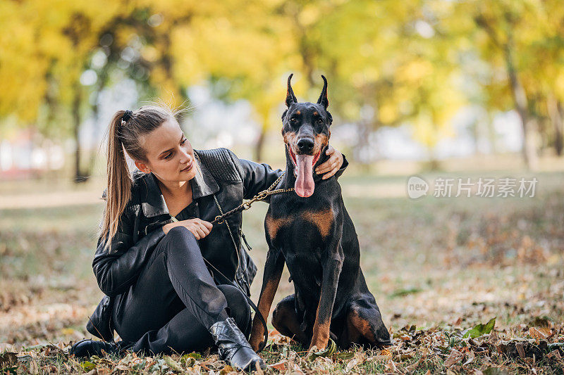 一个女人在公园里和她的杜宾犬玩耍