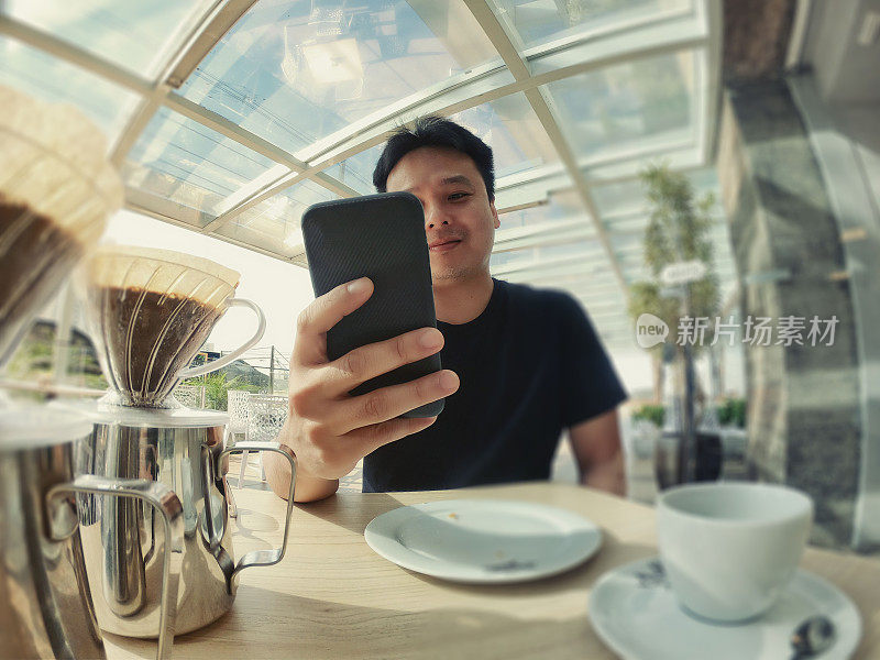 一名日本男子在咖啡店玩手机。