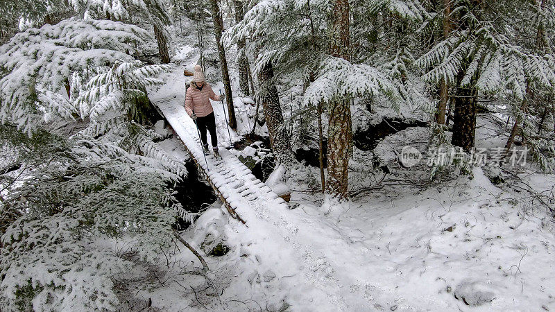 女性徒步旅行者走在被雪覆盖的木板路上