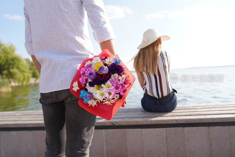 那个快乐的男人在公园里给一个女人送花。一个男人在一个夏日给他的爱人送花的照片。浪漫的情侣