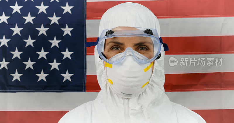劳累过度，在一天紧张工作后戴着防护眼镜和面具的成熟女性医护人员，背景是美国国旗