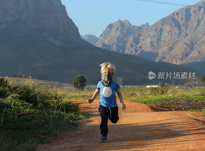 一个小男孩戴着面具在山里跑步