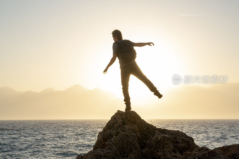 日出时分，徒步旅行者在阳光明媚的海岸峭壁上放松