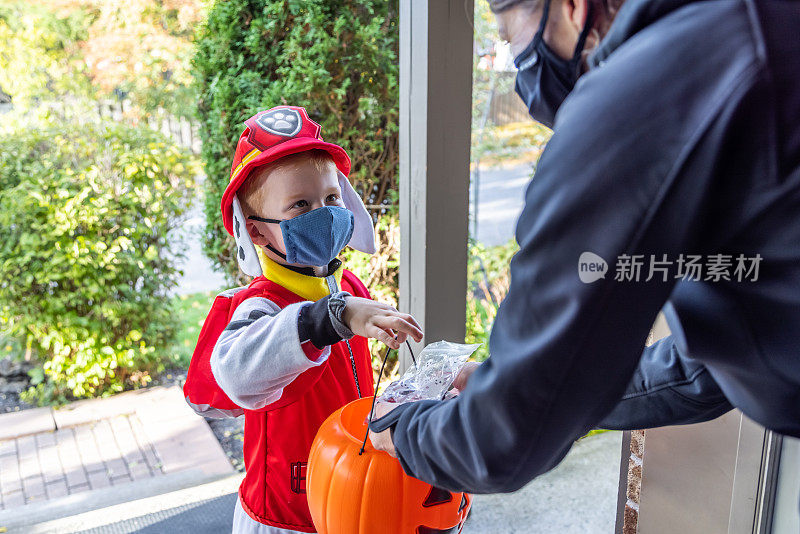 小男孩戴着防护面具在万圣节接受糖果