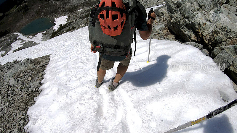 徒步旅行者沿着积雪的山坡跑下去