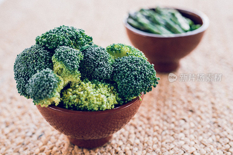 特写花椰菜和芦笋在碗里，背景是拉菲酒