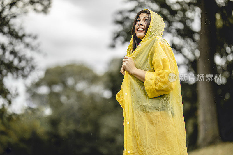 快乐年轻美丽的女人有乐趣，而在雨中跳舞在大自然